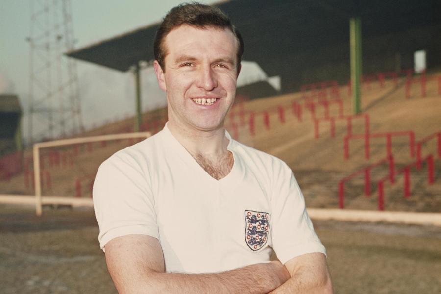Photo of Jimmy Armfield CBE, arms folded wearing an England Football shirt smiling at the camera